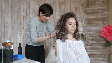 化妆师和模特一起工作。 理发师做模特的发型。 美发师发型师